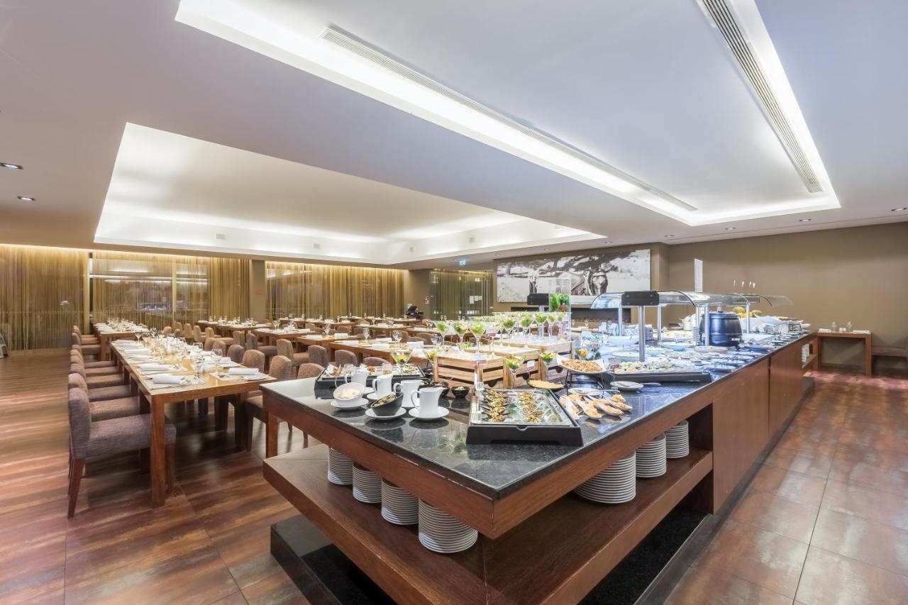 Ap Lago Montargil - Conference & Spa Экстерьер фото The photo displays a spacious restaurant interior, featuring a well-organized dining area with multiple tables set for patrons. In the center, there is a large buffet station filled with an array of food items. The decor is modern and elegant, with w
