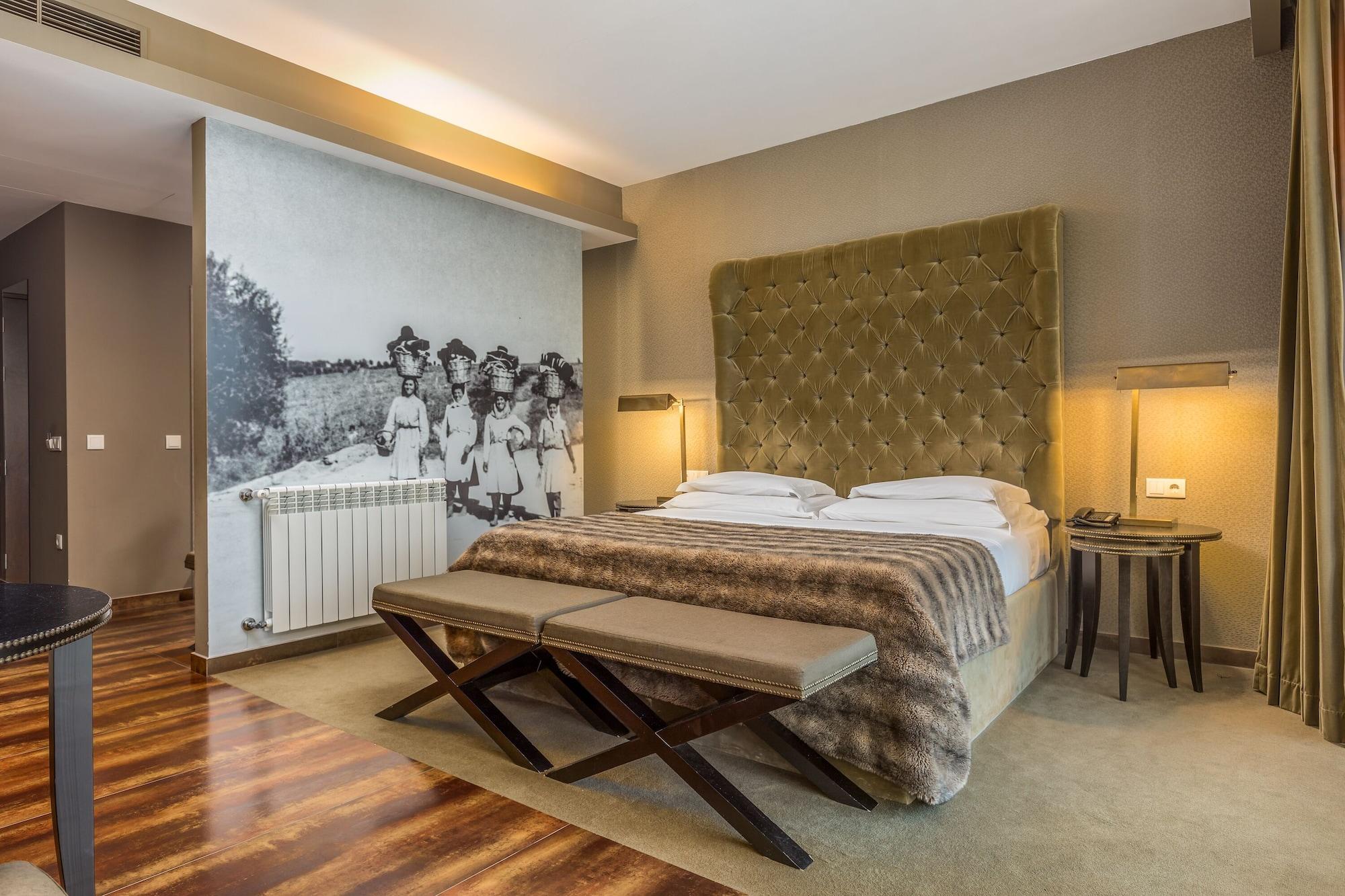 Ap Lago Montargil - Conference & Spa Экстерьер фото The photo shows a modern hotel room with a large, plush bed that has a tufted, green headboard. The bedding is white with a textured blanket at the foot of the bed. A decorative wall behind the bed features a black and white mural of children in a fi