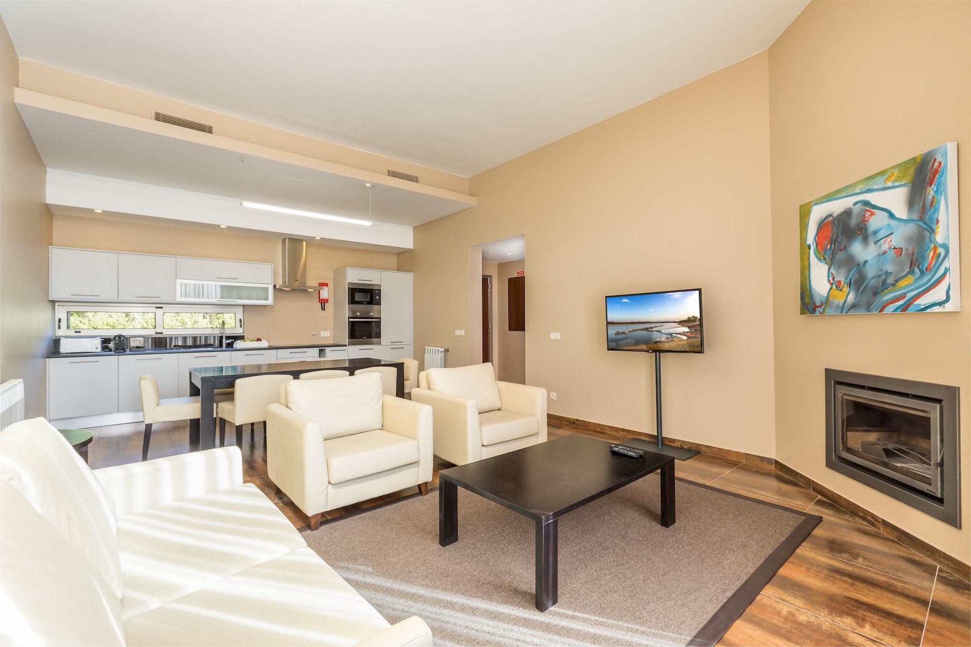 Ap Lago Montargil - Conference & Spa Экстерьер фото The photo shows a modern, spacious living area with a contemporary design. The room features light-colored walls and wooden flooring. 

In the center, there is a black coffee table surrounded by four white armchairs. A flat-screen TV is mounted on th