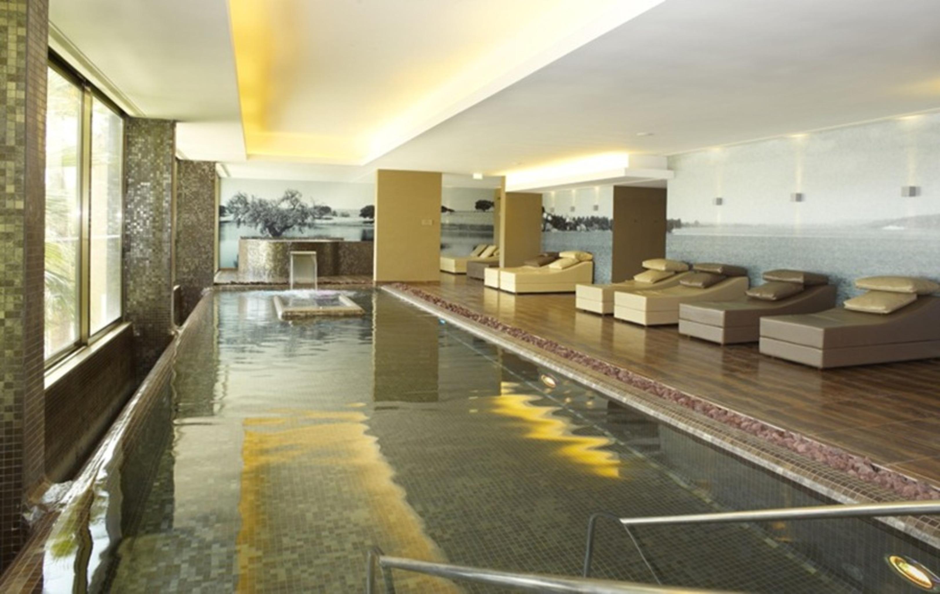 Ap Lago Montargil - Conference & Spa Экстерьер фото The photo shows a modern, serene spa environment. There is a swimming pool with calm water, reflecting the surrounding decor. Along the sides, there are several comfortable lounge chairs arranged, perfect for relaxation. Large windows allow natural l